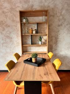 a wooden table with yellow chairs and a shelf at La Château de Toile, Gîte du Marronnier in Hersin-Coupigny