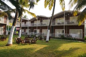 a resort with tables and chairs and palm trees at Shaan Coco Palms Beach Resort in Morjim