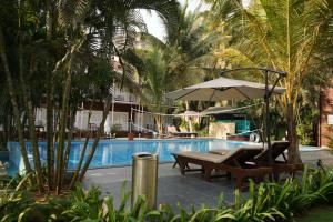 a pool with a chair and an umbrella and a table at Shaan Coco Palms Beach Resort in Morjim