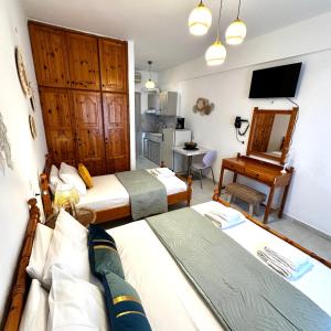 a room with two beds and a desk and a television at Liberty Studio in Kallithea Halkidikis