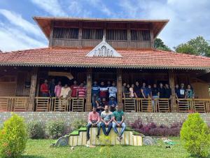 a group of people sitting on the porch of a building at JackRoot Athirappilly in Kallana +8 photos