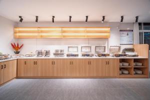 a large kitchen with wooden cabinets and appliances at Zhangjiajie Homeinn Hotel- New Hotel,Free Breakfast, Free Self-Service Laundry & Drying, Attraction Tickets Serivce in advance,Toursim info in Zhangjiajie