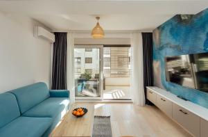 a living room with a blue couch and a tv at Azure Bay in Igalo