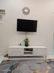 a living room with a tv on a white wall at Dhila Homestay Jalan Pasir Mas Rantau Panjang in Pasir Mas