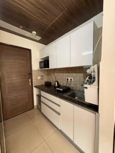 a kitchen with white cabinets and a sink at AeroNest Luxe in Zirakpur