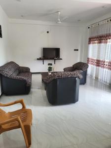 a living room with two couches and a tv at Villa Olive in Hikkaduwa