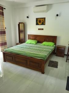 a bedroom with a large bed with green sheets at Villa Olive in Hikkaduwa