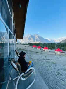 a person sitting in a chair on the beach at Oasis Resort in Skardu