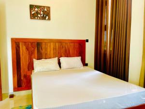 a bed with a wooden headboard in a room at Green Crown Villa in Polonnaruwa