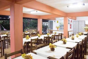 a dining room with white tables and wooden chairs at Pousada Canto das Aguas in Serra do Cipo