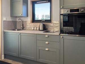 a kitchen with gray cabinets and a window and a sink at Wee Shore Walk in Balintore