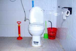 a bathroom with a white toilet and a red bucket at Tenzi BnB in Jinja +26 photos