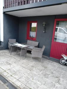 a patio with a table and chairs and a red door at Ferienwohnung Schimpf in Sosberg +7 photos