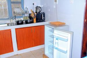 a kitchen with a refrigerator and a microwave at Tenzi BnB in Jinja