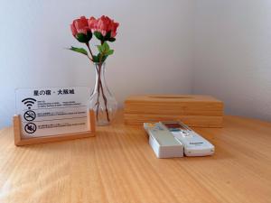 a remote control next to a box and a vase of flowers at 星の宿大阪城 in Osaka +13 photos