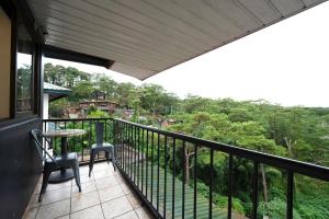 a balcony with a table and chairs and trees at 3BR The South Drive Loft 301 in Baguio