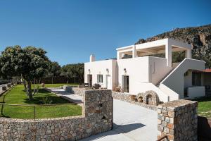 a large white house with a stone wall at Casa Horizon in Palaiochora