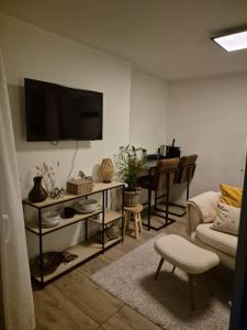 a living room with a couch and a tv on the wall at Studio Zebra in Heikant +3 photos