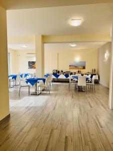 a dining room with blue tables and white chairs at La Giara Guest House in Marina di Modica