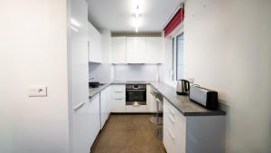 a kitchen with white cabinets and a black counter top at Sky One La Defense in Courbevoie