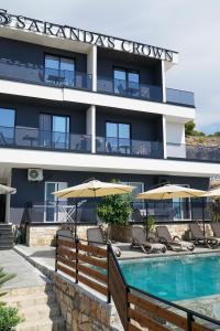 a hotel with a swimming pool and chairs and umbrellas at Saranda's Crown in Sarandë