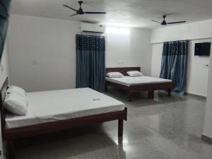 two beds in a room with blue curtains at Akshay Hotel in Bikaner