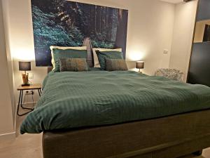 a large bed with a green comforter in a bedroom at GuestHouse Groenplaats in Antwerp