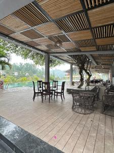 a wooden deck with chairs and tables and a tree at Khu Nghỉ Dưỡng Ivory Villa Resort in Lương Sơn