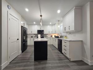 eine Küche mit weißen Schränken und einem schwarzen Kühlschrank in der Unterkunft Elegant 3-bedroom Home Away From Home, Luxury Styled in St. John's + 14 Fotos