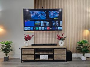 Ein Fernseher auf einem Entertainment-Center mit zwei Vasen. in der Unterkunft Elegant 3-bedroom Home Away From Home, Luxury Styled in St. John's