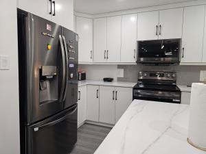 eine Küche mit einem Edelstahlkühlschrank und einer Mikrowelle in der Unterkunft Elegant 3-bedroom Home Away From Home, Luxury Styled in St. John's