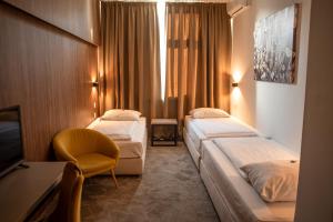 a hotel room with two beds and a tv at Hotel Sliško in Zagreb
