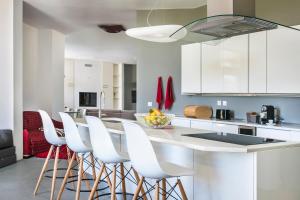 a kitchen with white cabinets and a counter with stools at Villa Katrin in Svoronata