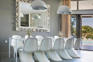 a dining room with a white table and white chairs at Villa Katrin in Svoronata +18 photos