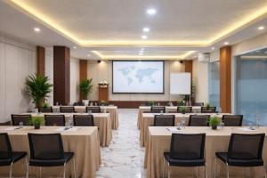 a conference room with tables and chairs and a screen at Hotel & Resto Marza 88 in Pangkajene