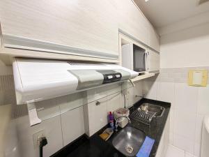 a small kitchen with a sink and a microwave at Santorini Piscina Hidro Academia Salt Hospital Premium Jaime Câmara Mercatto Store Moreira Marista Blue Fit Perdomo Vaca Brava Goiânia Shopping Areião Marista Ze Abílio Serrinha Campo do Goiás Hailé Pinheiro in Goiânia