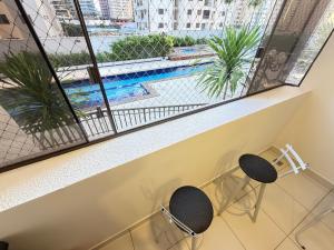 a balcony with two chairs and a swimming pool at Santorini Piscina Hidro Academia Salt Hospital Premium Jaime Câmara Mercatto Store Moreira Marista Blue Fit Perdomo Vaca Brava Goiânia Shopping Areião Marista Ze Abílio Serrinha Campo do Goiás Hailé Pinheiro in Goiânia