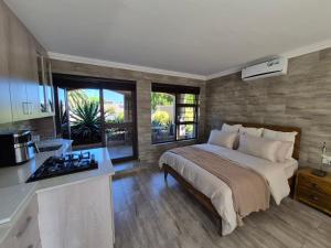 a bedroom with a large bed and a kitchen at Somerset Garden Studio in Somerset West