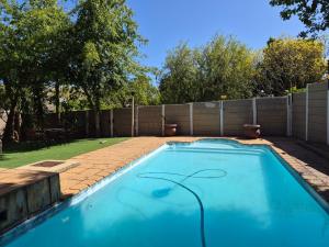 a swimming pool in a backyard with a fence at Somerset Garden Studio in Somerset West