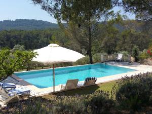 een zwembad met een parasol en 2 ligstoelen en een parasol bij Modern Villa With Swimming Pool in Salernes France in Salernes