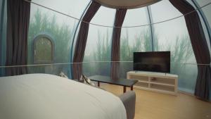 a bedroom with a large window with a bed and a tv at Arkaluna Resort & Adventure in Kintamani +29 photos