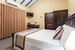 a bedroom with a large white bed and a television at Karanda Eco Resort in Dambulla