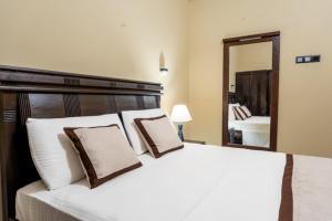 a bedroom with a white bed with pillows and a mirror at Karanda Eco Resort in Dambulla