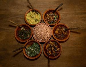 a group of bowls of food on a wooden table at Karanda Eco Resort in Dambulla +52 photos