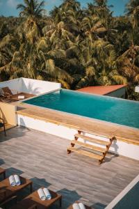 a swimming pool with a table and chairs and palm trees at Cozy Roots Fuvahmulah in Fuvahmulah
