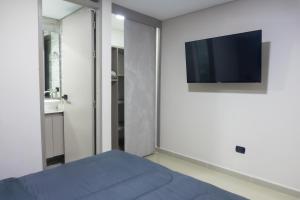 a bedroom with a bed and a tv on the wall at NOVA Apartahotel in Medellín