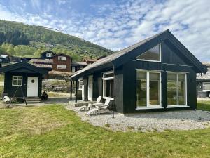 a black house with windows and a grass yard at Hytte sentralt i Myrkdalen in Vossevangen