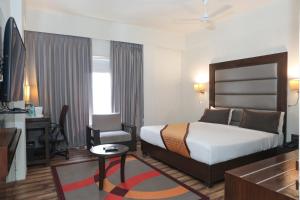 a hotel room with a large bed and a desk at Veronica Hotel in Vadodara +26 photos