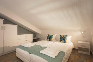 a bedroom with a white bed with a green blanket on it at Dreamy Seaside Loft Pool, Parking, Fast Wifi in Gouvia +19 photos