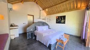a bedroom with a bed and a chair in a room at Penida View Village - Infinity pool & Volcano View in Nusa Penida